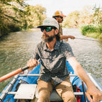 Howler Brothers Aperture Tech Strapback Hat in Bahía de Howler / Stone worn outdoors near the water