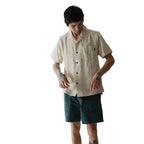 Full-body view of a man wearing the KAVU Deckhouse Short Sleeve Shirt in Tropical Sands for travel, resort wear, and casual summer adventures