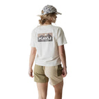 Full-body view of a woman wearing the KAVU Leilani Short in Daisy Love for summer travel, casual outings, and warm-weather adventures