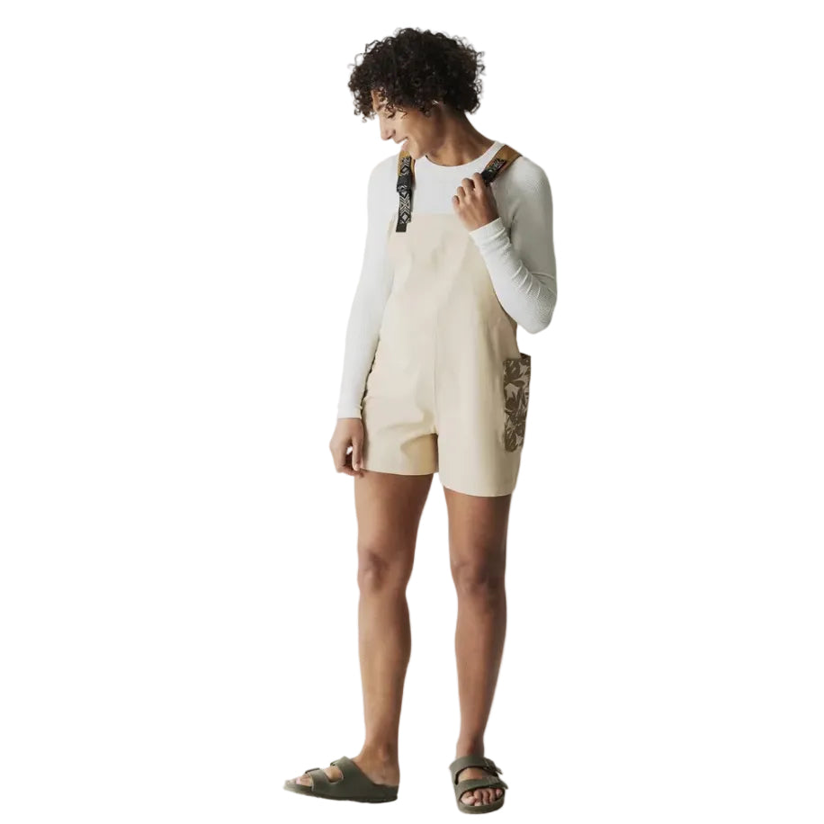 Full-body view of a woman wearing the KAVU Montanita Overall in Beige Palm for travel, casual outings, and outdoor adventures